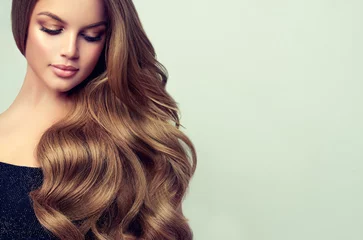 Crédence de cuisine en verre imprimé Salon de coiffure Fille brune aux cheveux ondulés brillants longs et volumineux. Beau modèle de femme avec une coiffure frisée.
