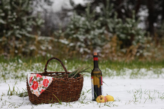 Picnic in the field on the first snow. The composition includes red wine, oats, apples.