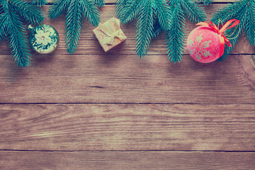 Christmas background. Branches of a Christmas tree, ball and gift boxes on a wooden background with copy space.