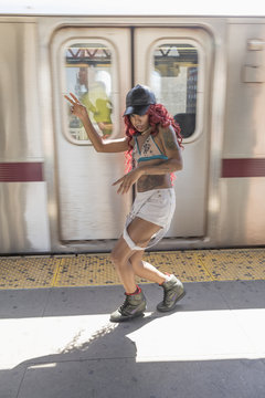 Young woman dancing beside a subway train