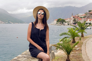 beautiful young girl sitting in hat on the background of mountains and sea