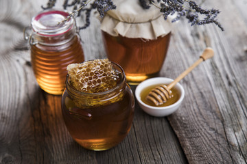 Honey in jar with honey dipper on wooden background 