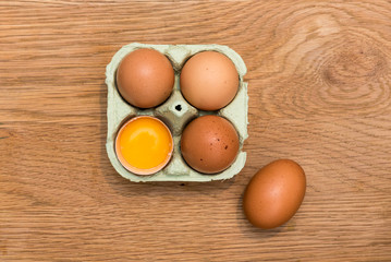 Close-up view of raw chicken eggs in egg box on  oak wooden background