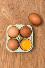 Close-up view of raw chicken eggs in egg box on  oak wooden background