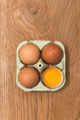 Close-up view of raw chicken eggs in egg box on  oak wooden background