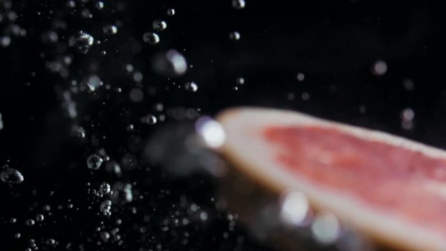 Round fresh juicy grapefruit slice plunging into transparent water with explosive stunning splash. Underwater high-speed slow motion shot on black background. Pomelo isolated.