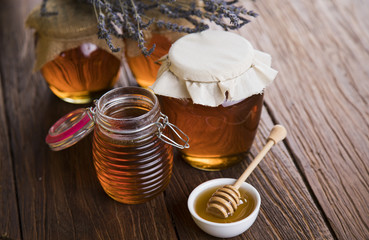 Honey in jar with honey dipper on wooden background 