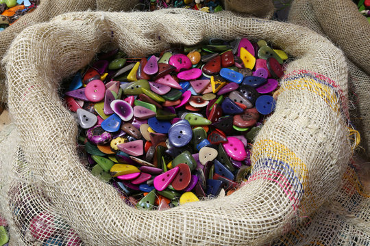 jute bag full of buttons made with colored palm seeds