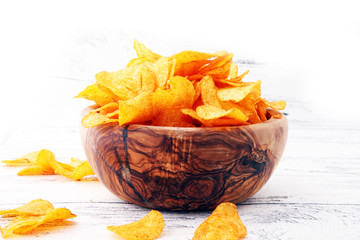 Crispy potato chips. Paprika chips on white wooden background.