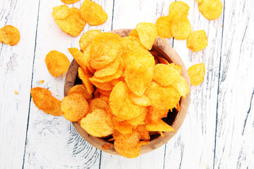 Crispy potato chips. Paprika chips on white wooden background.
