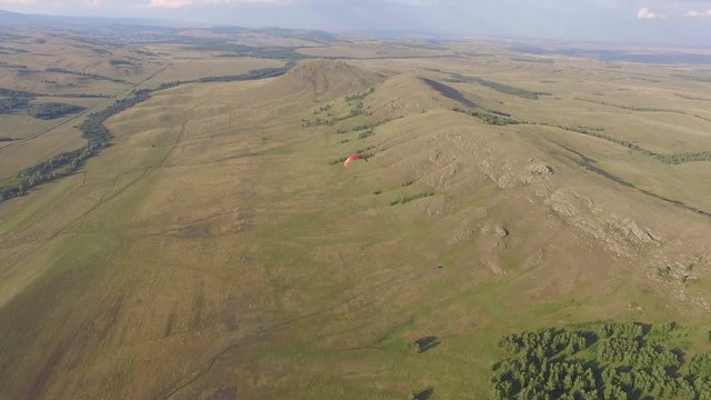 AERIAL: The paraplane flight above endless plains and mountains. Beautiful summer landscape of Bashkortostan, Russia. 