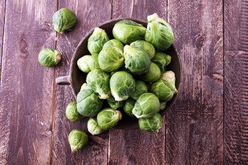 Fresh brussel sprouts over rustic wooden texture and in a vintage bowl.
