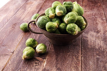 Fresh brussel sprouts over rustic wooden texture and in a vintage bowl.