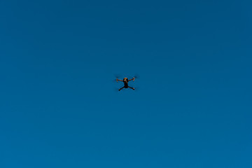 Naklejka na ściany i meble Drone flies in a blue sky