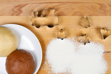 Christmas cookie cutter in different shapes, top view, on wooden board with flour