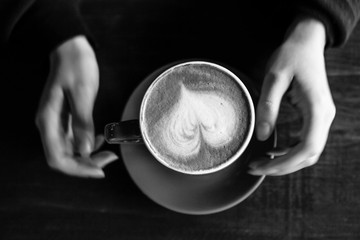 flatlay woman holding cappuccino coffee in black and white