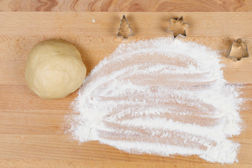 Christmas cookie cutter in different shapes and dough, top view, on wooden board with flour