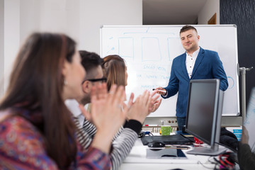 Young business people applauding to their colleague after successful presentation on a meeting