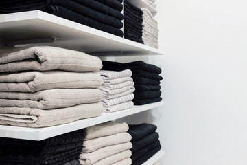 a pile of cotton towels on white shelf  