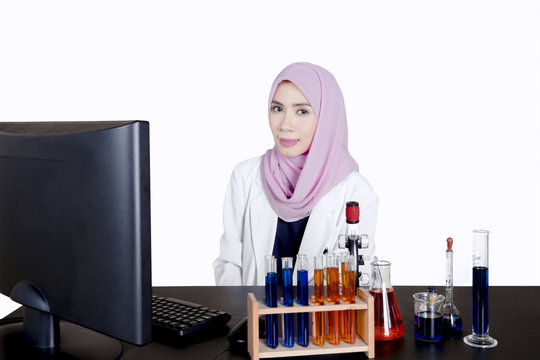 Young muslim scientist with test tube on desk