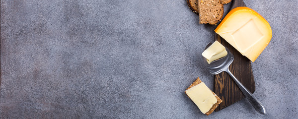 Delicious dutch gouda cheese with cheese slices, multigrain bread and special knife on old wooden...