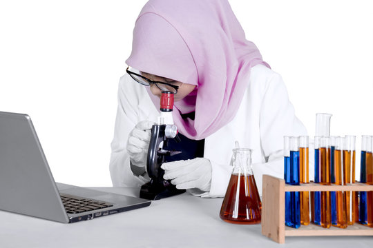 Scientist works with microscope and laptop