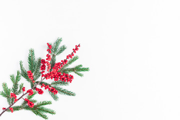 Christmas composition. Christmas pattern made of fir tree branches and red berries on white...