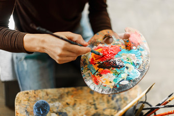 Caucasian artist putting red paint on his palette in the studio