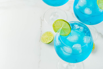Alcohol drink. Glasses with a blue alcoholic cocktail with ice and lime garnish. Blue Curacao. Liquor. Copy space