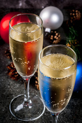 Dry Champagne in glasses, Christmas colorful balls, pine cones, New Year still life composition on dark stone background, selective focus copy space