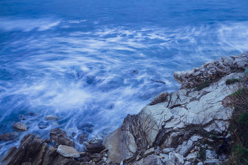 blue waves beat against rocks on long exposure