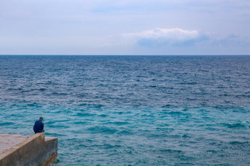 endless blue sea and man on  concrete pier