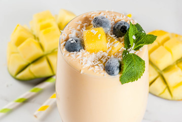 Dietary drink, breakfast. Tropical mango smoothie with fresh pieces of mango, blueberries, coconut...