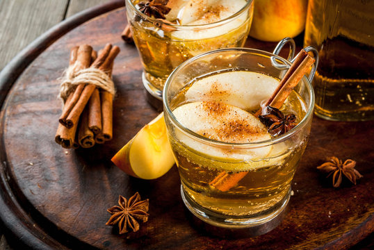Autumn and winter drinks. Traditional home-made apple cider, cocktail of cider with aromatic spices - cinnamon and anise. On an old wooden rustic table, on a tray. Copy space