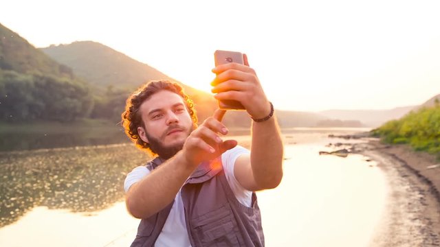 One fisherman makes a selfie on the sunset on a summer evening. Makes a photo of your rest