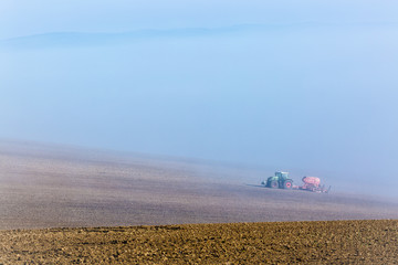 Fototapeta na wymiar Beautiful misty foggy autumn landscape with working tractor in south moravia, Czech Republic. Agriculture concept.