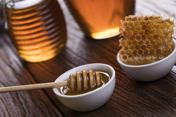 Honey in jar with honey dipper on wooden background 