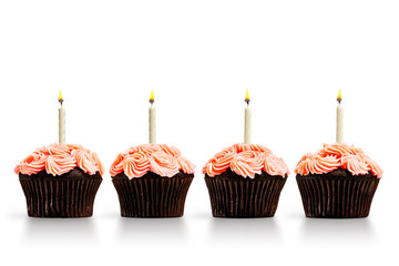 Row of pink cupcakes with lit candles isolated on white