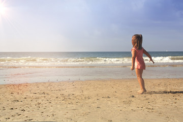 little girl having fun playing on the sea shore