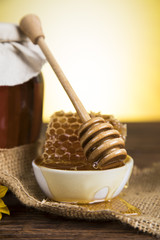 Honey in jar with honey dipper on wooden background 
