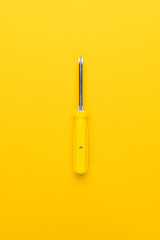 manual screwdriver with plastic handle on the yellow background