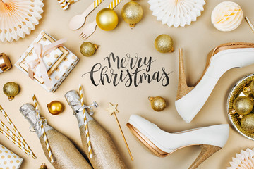 Flat lay stylish set: champagne, gift, female shoes, christmas balls and golden holiday decoration....