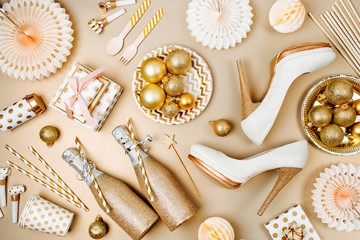 Flat lay stylish set: champagne, gift, female shoes, christmas balls and golden holiday decoration. Flat lay, top view.