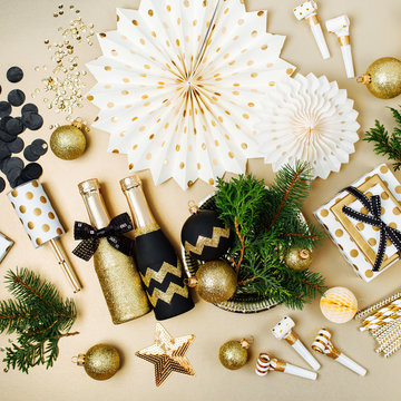 Flat lay stylish set: champagne, gift, female shoes, christmas balls and gold and black  holiday decoration. Flat lay, top view.