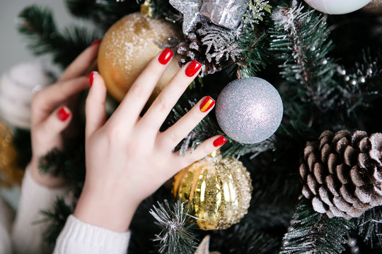 Manicure for the New Year in red against the background of Christmas trees and Christmas toys