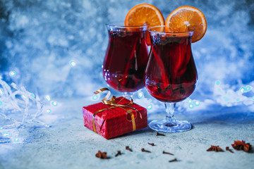 hot mulled wine with spices, orange and gift box on light background