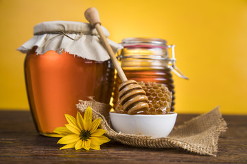 Honey in jar with honey dipper on wooden background 