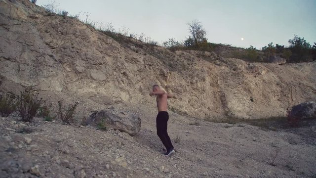 Strong man jogging on the rough rock and training free fight. 4K