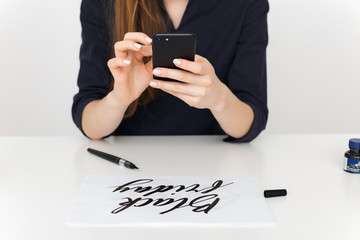 Close up photo of young woman hands that holding cellphone and paper on desk isolated