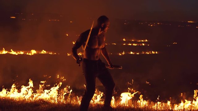 Military man shows performance with swords at bonfires. 4K